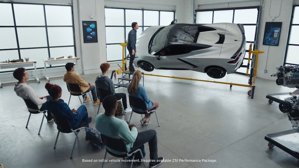 Group of People Looking at a Chevy Corvette Raised Up on a Lift