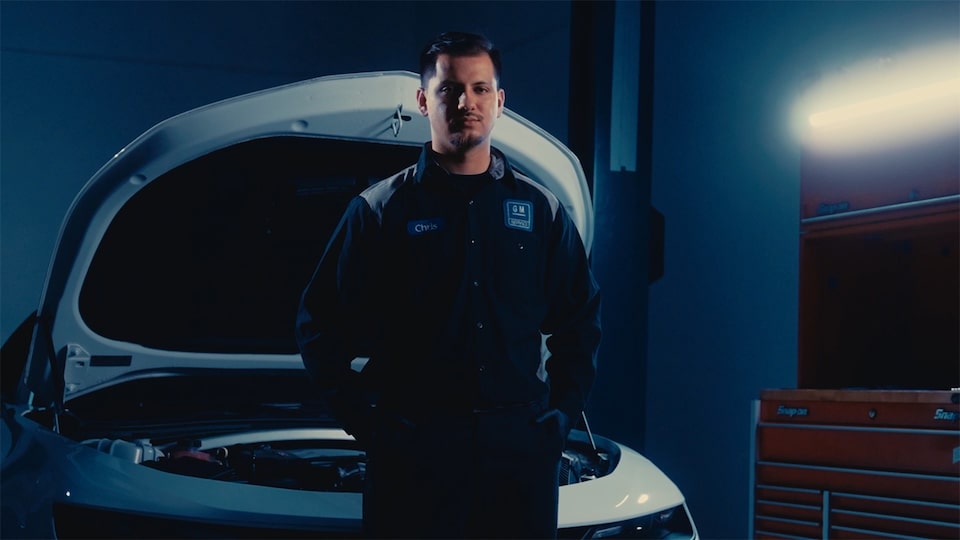 A Certified Service Apprentice Standing in Front of a Vehicle with the Hood Open