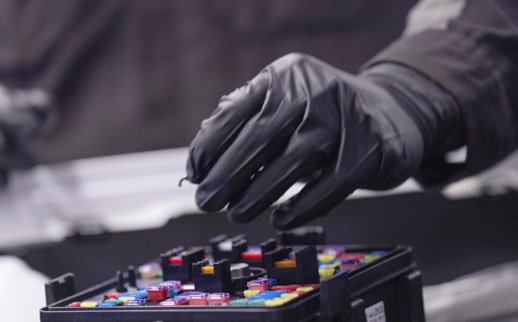 A Hand in a Black Glove Removing a Small Electrical Fuse from a Fuse Box