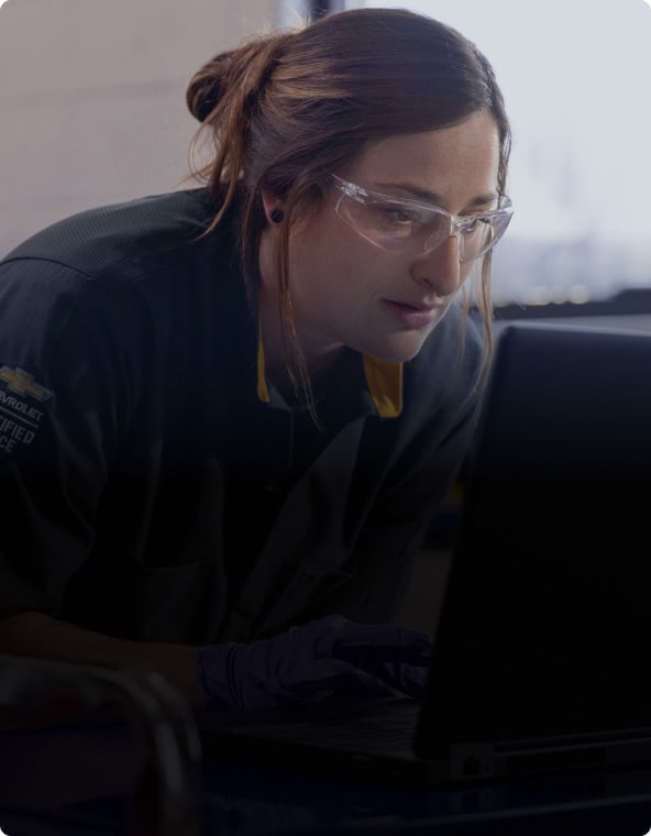 A Close-up of a Woman in Safety Glasses and a General Motors Certified Service Shirt