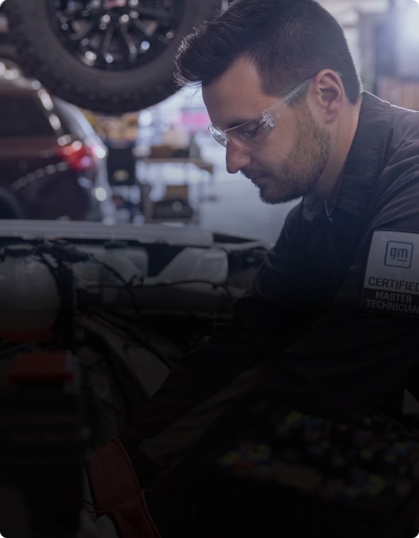 A Close-up of a Man in Safety Glasses and a General Motors Certified Service Shirt