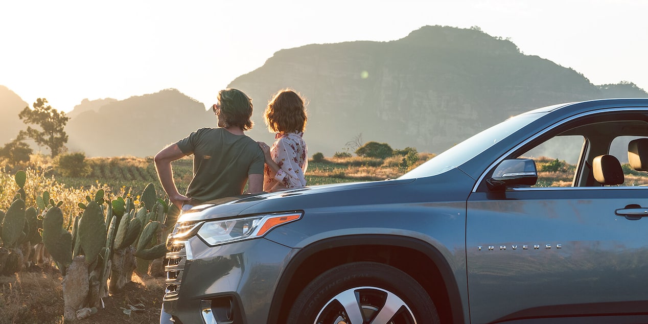 Man & Women Leaning Against Car Watching The Sunset