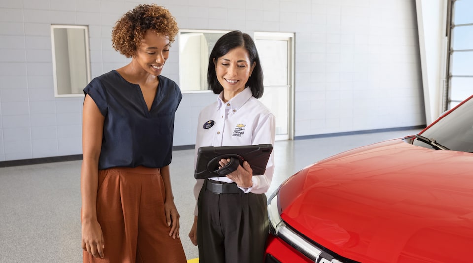 Two women standing in front of Chevy vehicle
