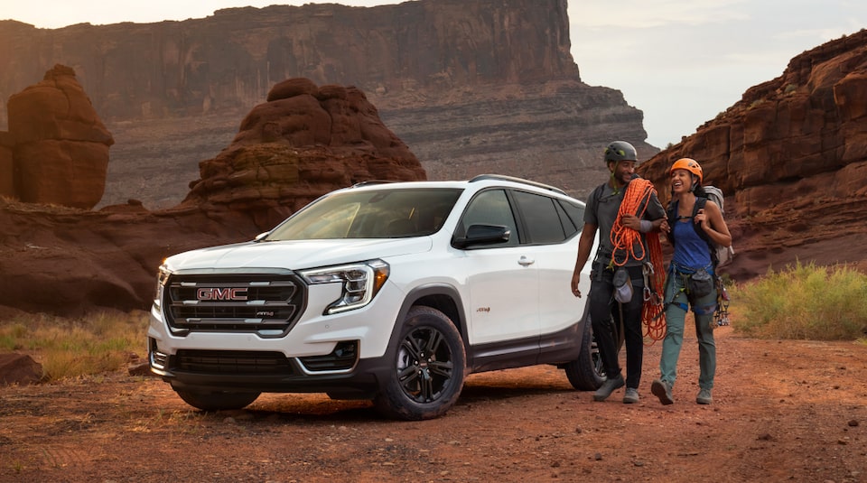 Couple rock climbing next to their GMC vehicle