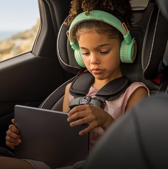 Image of a little girl in the back seat of a car on a tablet