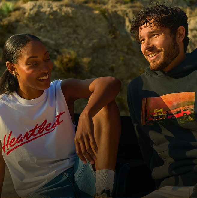 Woman in white 'Heartbeat' shirt and man in black sweatshirt smiling and laughing