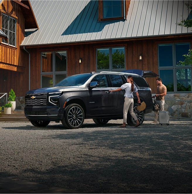 Image of a couple outside a house with a parked Chevrolet