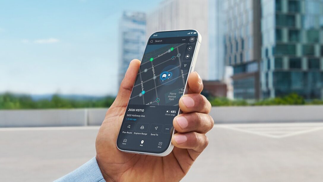 A hand holds a smartphone displaying the OnStar Guardian mobile app, which shows a map with a car icon and a location pin in a parking lot, demonstrating the vehicle locate feature.