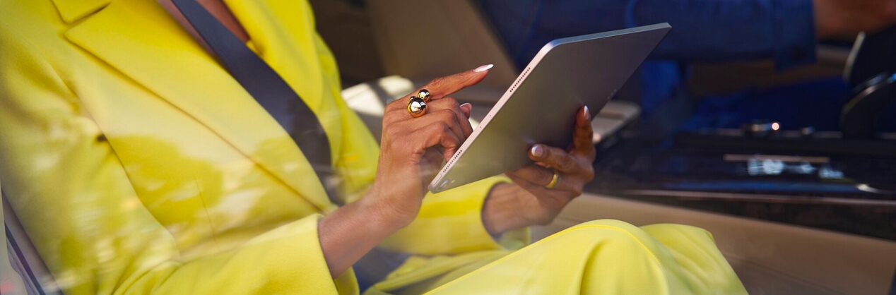 A person in a yellow suit holding a tablet device.