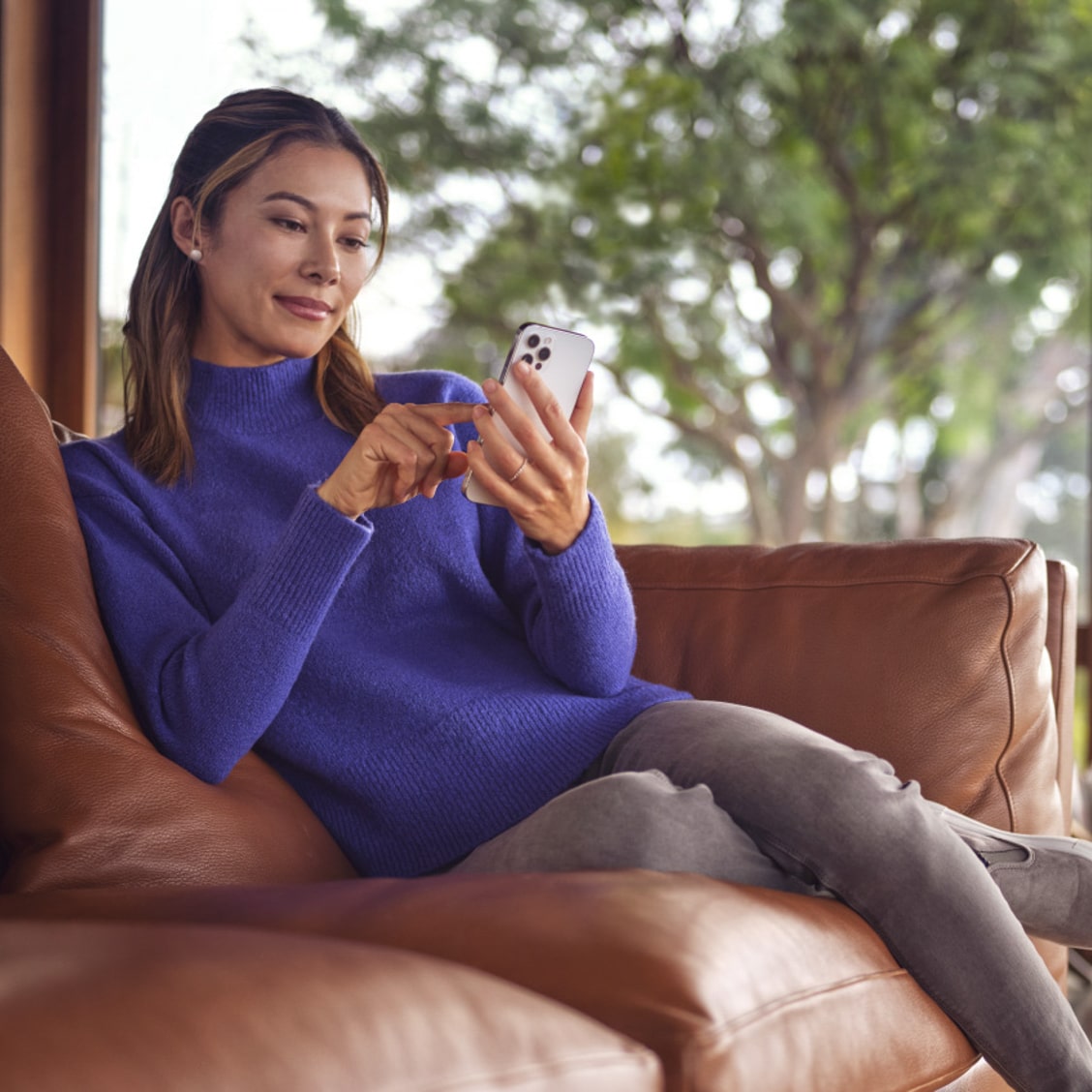 Woman Wearing Blue Sweater Sitting On Her Phone