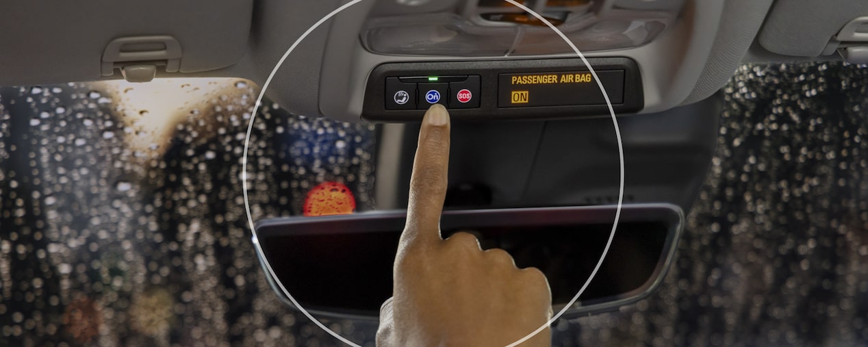 Close-Up Of Hand Pressing OnStar Button With Rainy Windshield