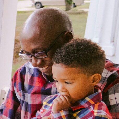 Father & Son Looking Down While Sitting Close Together