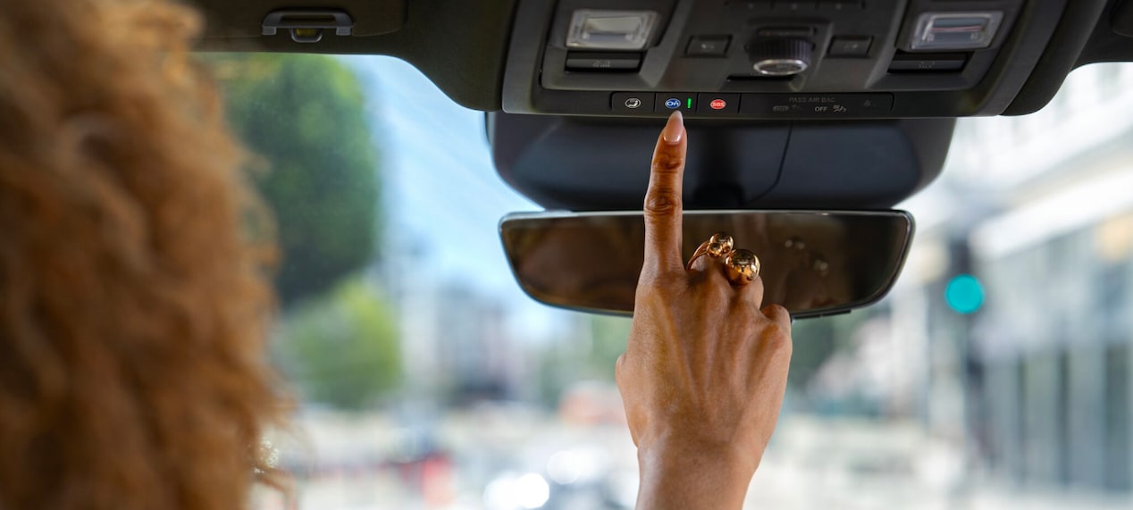 Woman pressing the OnStar button in her vehicle