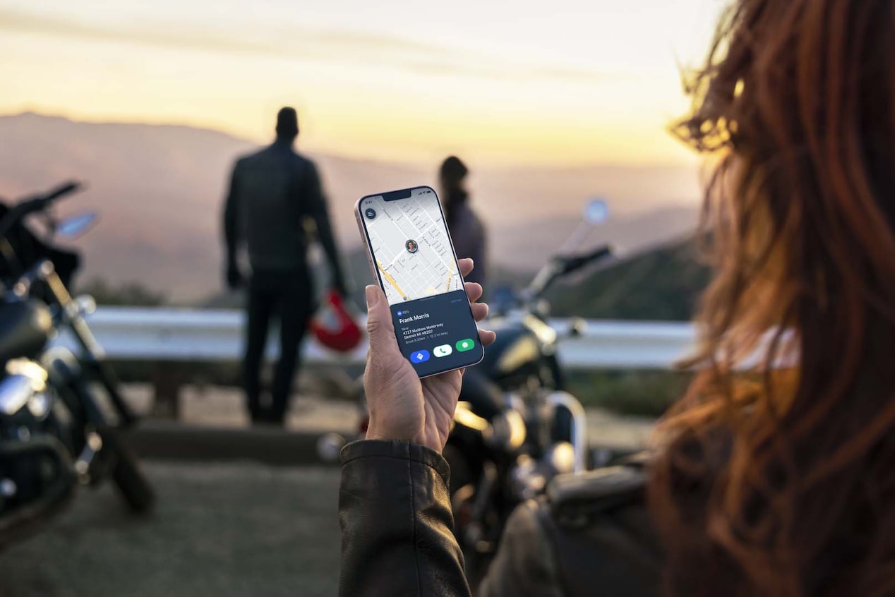 Women Standing Next to Motorcycle Using Smartphone Displaying a Map 