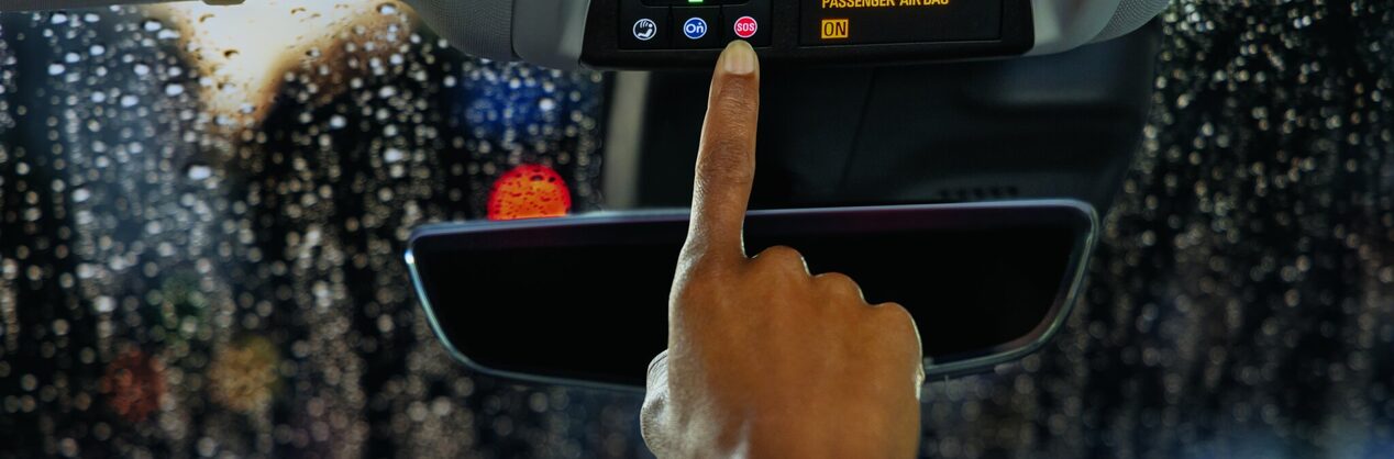 Close-up of a hand with one finger reaching out for the OnStar button