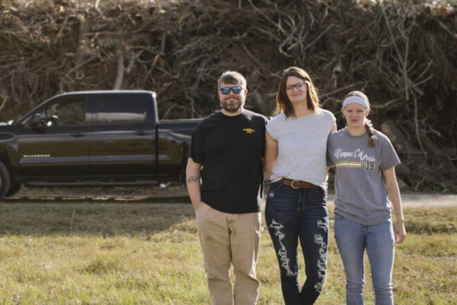A family standing in front of their truck on the lawn