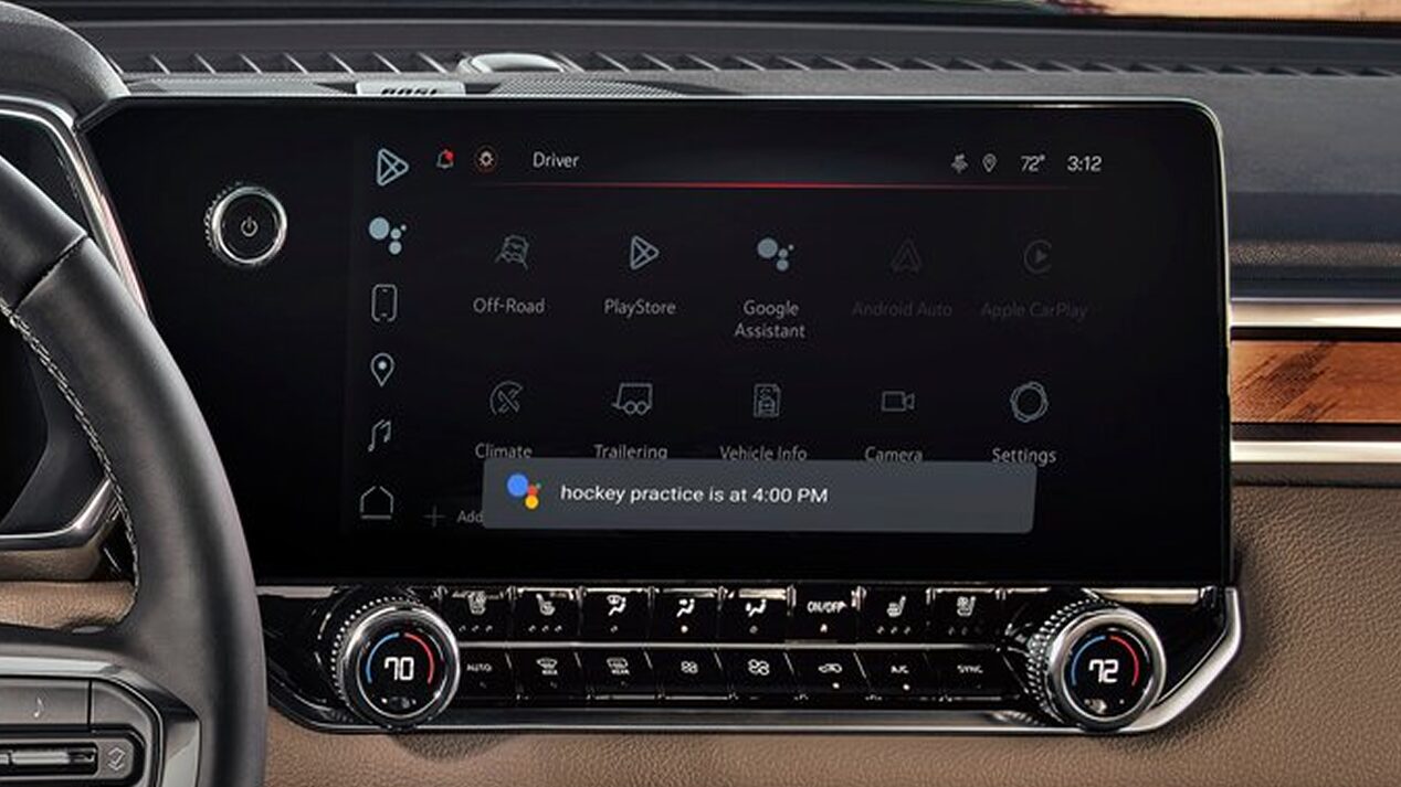 The vehicle's infotainment screen shows a selection of apps like Google Play and Google Assistant, with a notification "I have something to tell you."