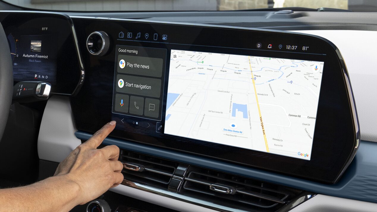 A hand interacts with the vehicle's infotainment screen, which displays Google Maps navigation and a Google Assistant button.