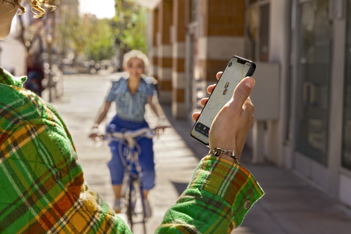 User Checks Guardian App While Friend Approaches on a Bike