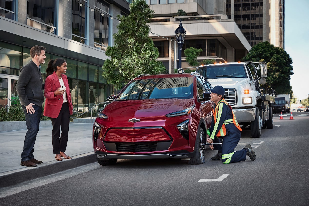 Roadside Assistance Works on a Chevy in Front of an Office Building