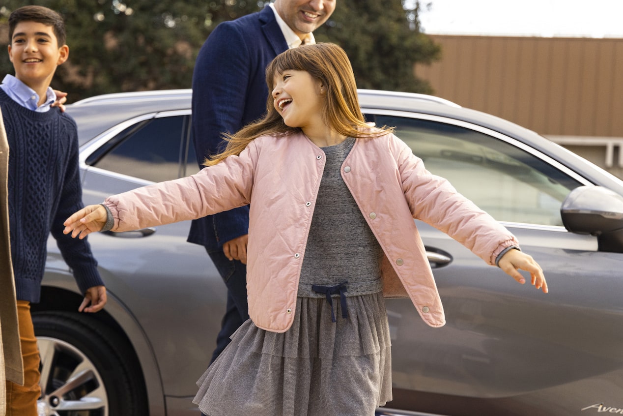 Little Girl in a Pink Jacket Twirling While Walking With Family