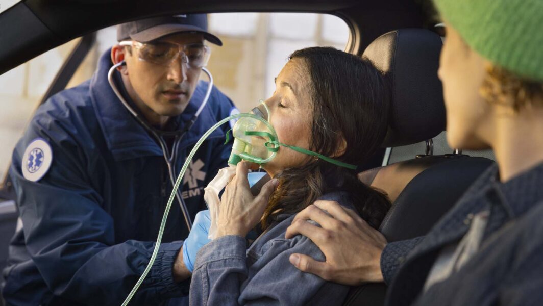 Close up of EMT Giving a Woman Oxygen with an Air mask in her Vehicle