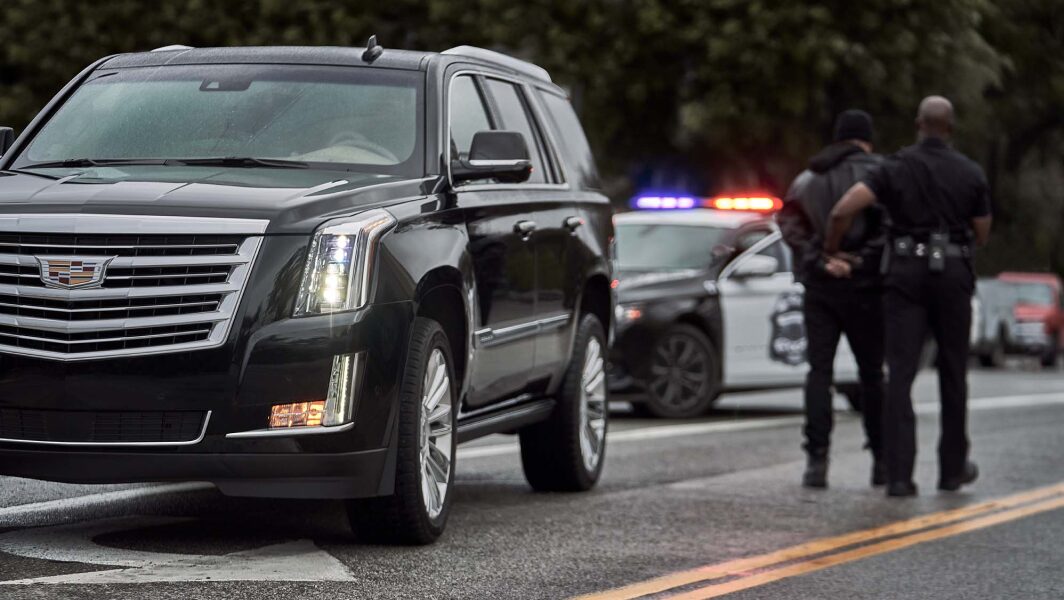 Man getting arrested next to Cadillac