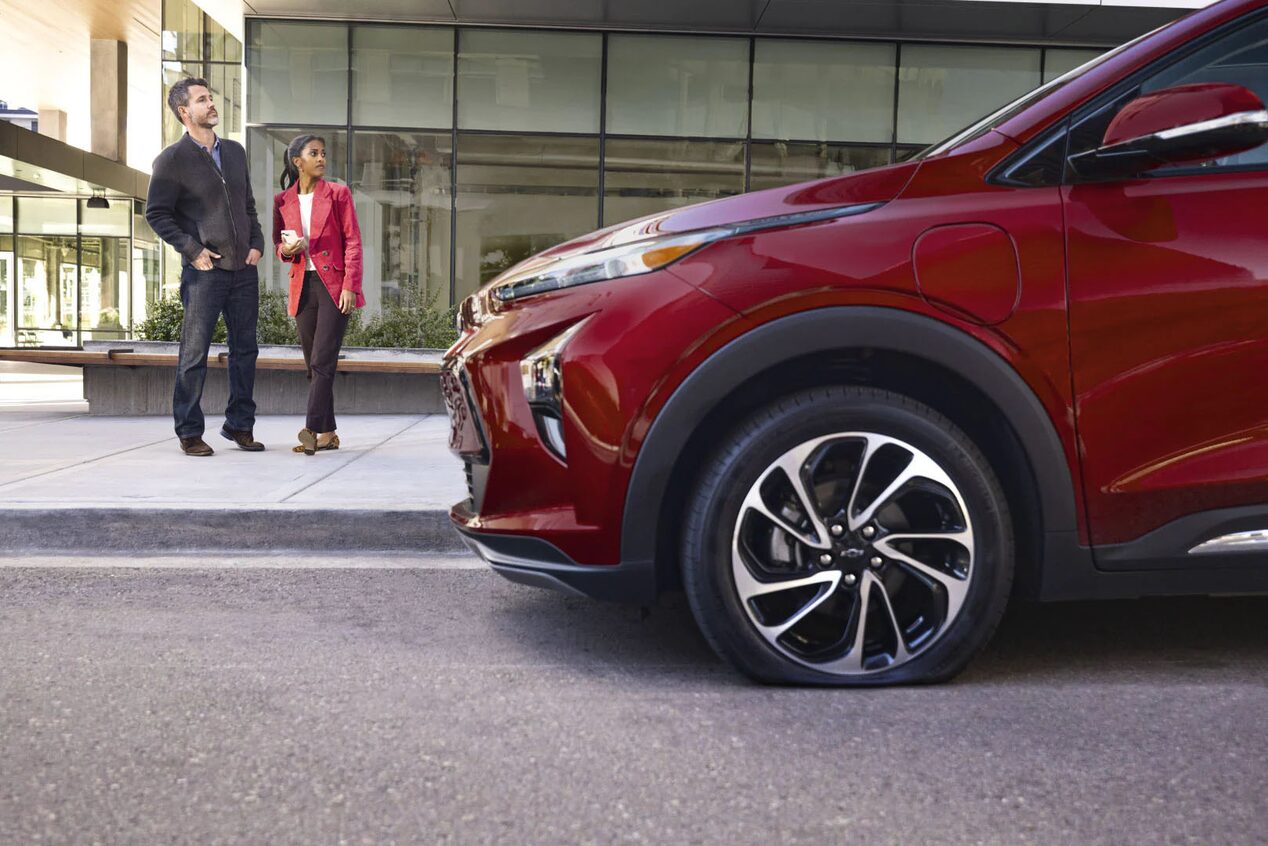 Couple Standing on Side Walk Next to GM Vehicle