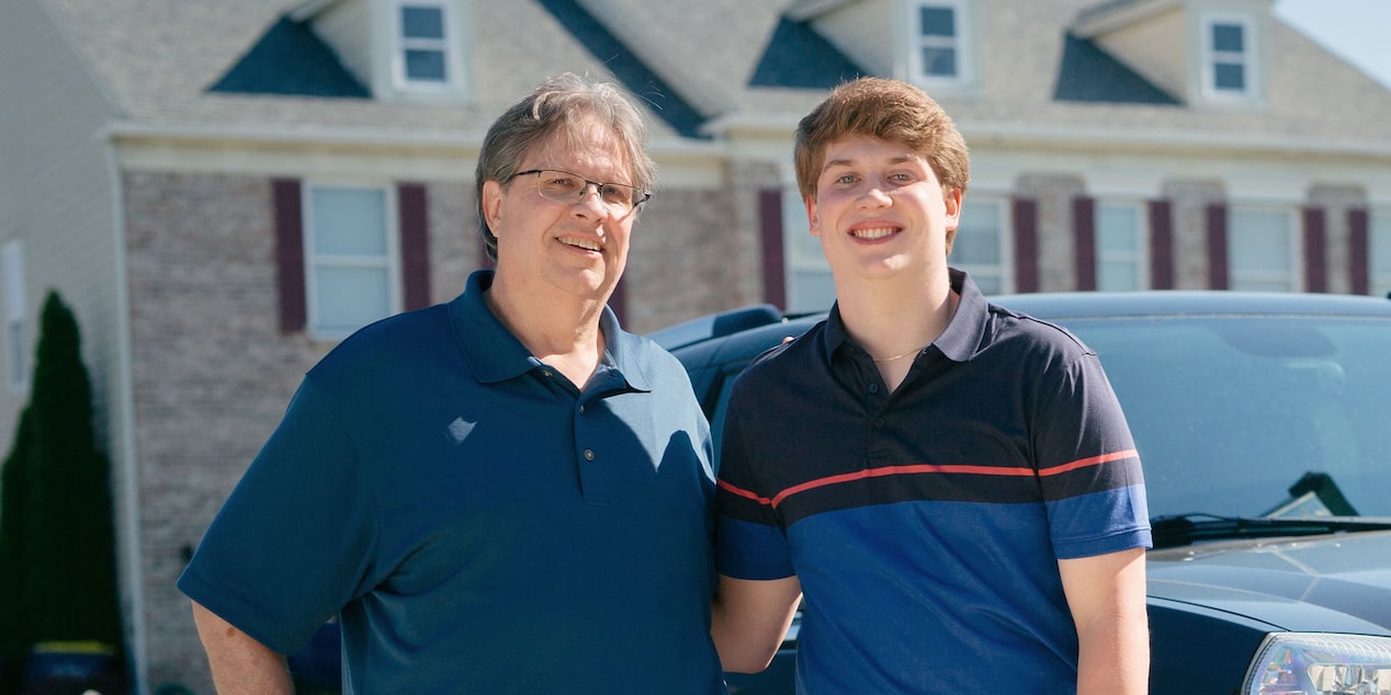 Father and Son Standing Side by Side in Driveway Smiling