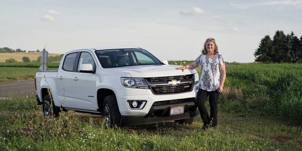 Woman Standing Smiling Near the Front of Her Chevy Truck