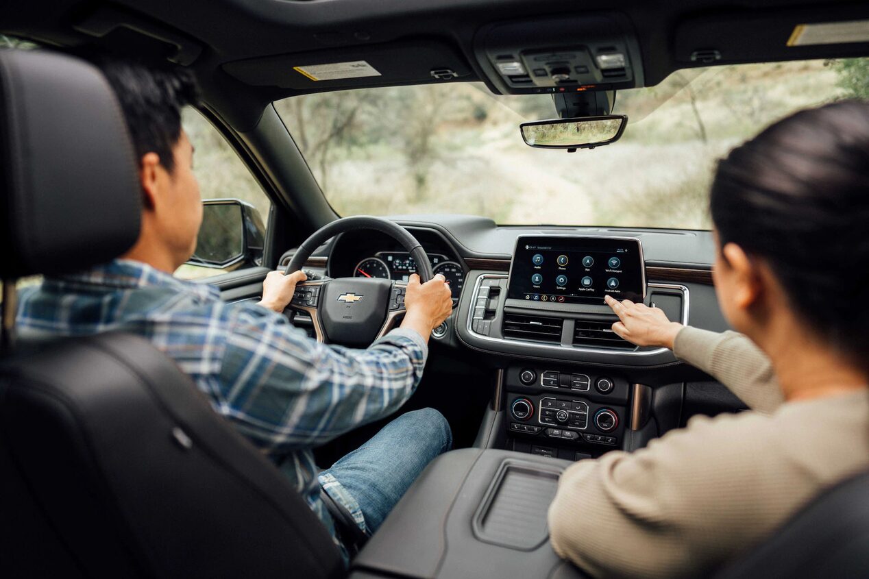 Man Driving While Women in Passenger Seat Points at the Infotainment System