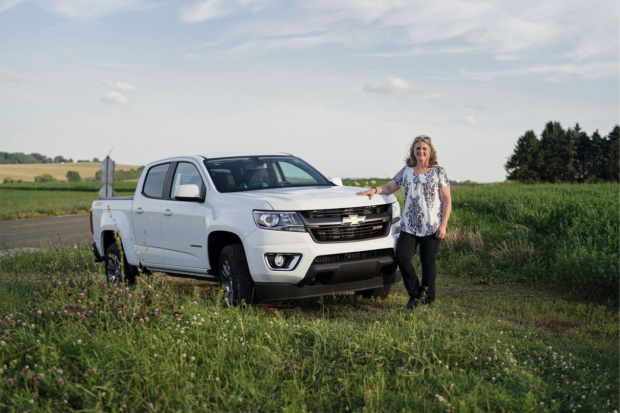 Woman Standing Next to Her Chevy Truck in a Field 