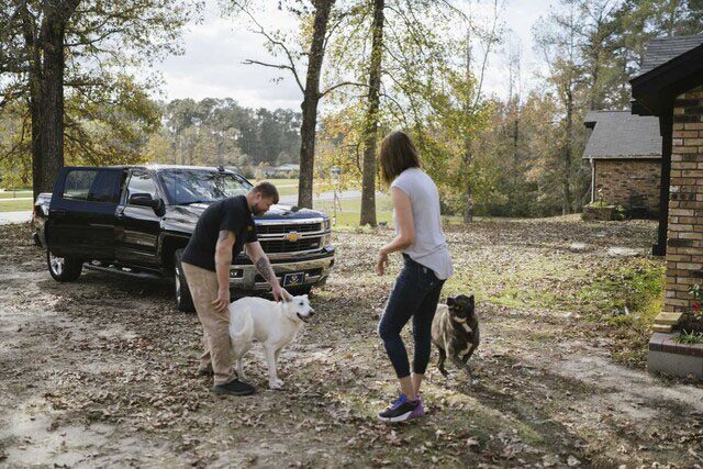 Couple in Driveway Playing with Their Dogs