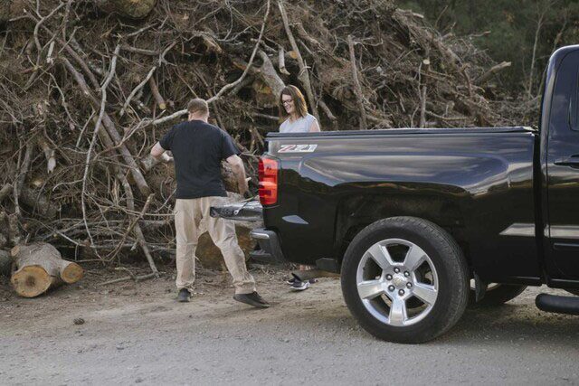 Couple Unloading Wood From Chevy Pickup Truck 