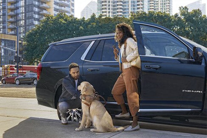 A man and woman stepping out of their vehicle with their dog