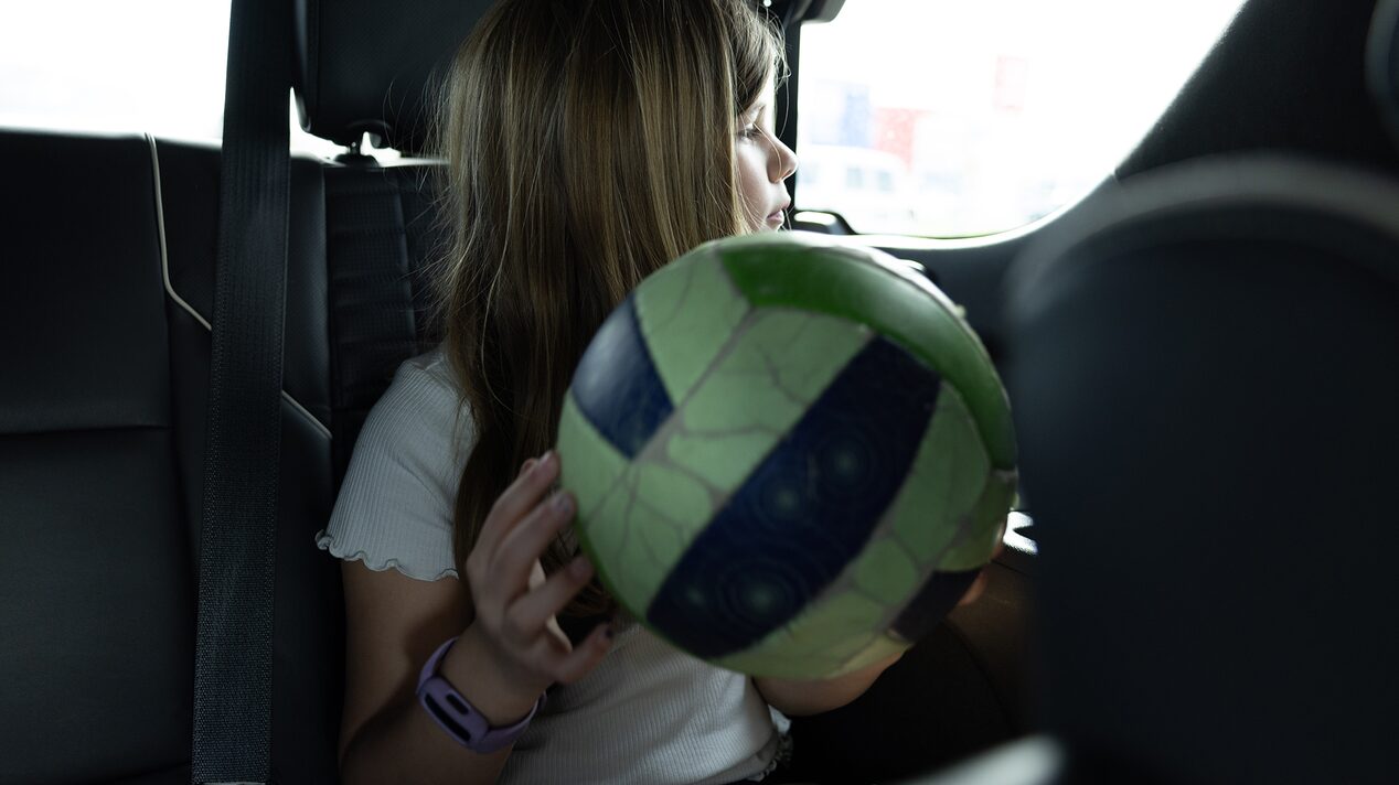 Justin's youngest daughter sitting in their Cadillac Escalade holding a volleyball