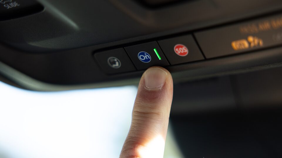 Close-up of Justin pressing the OnStar button in his Cadillac