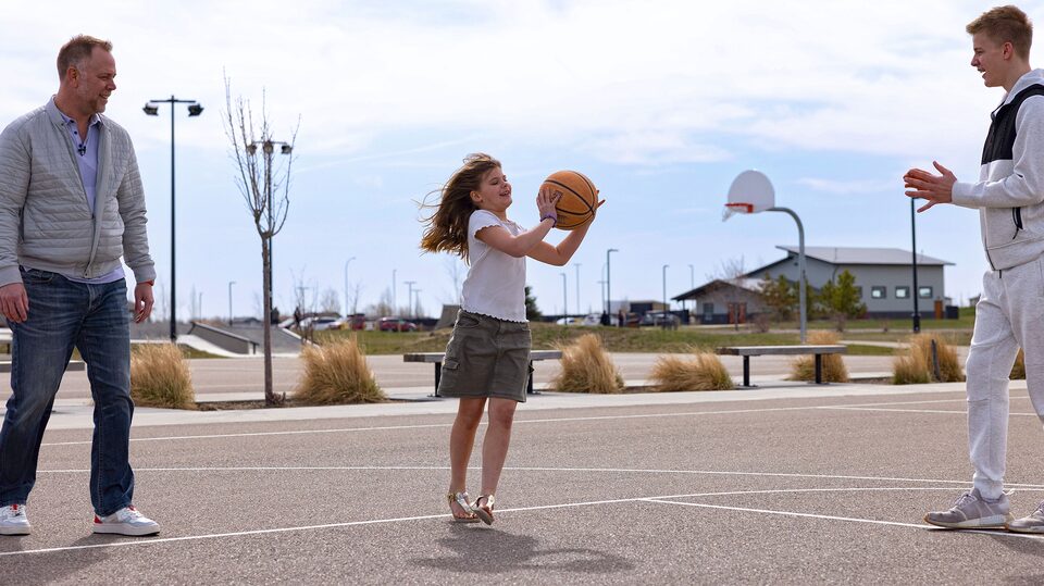 Justin and two of his kids playing basketball at a park