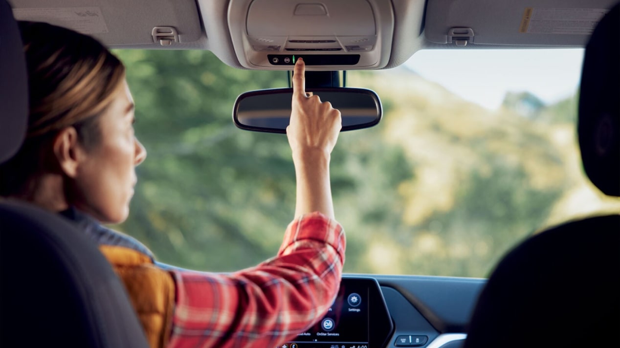 Female Driver Wearing Red Flannel Pressing the OnStar Button 