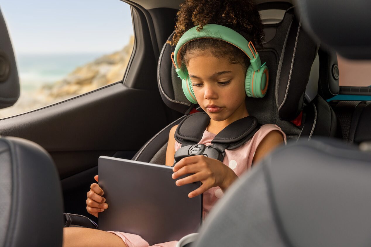 Little Girl in Car Seat Using iPad and Headphones