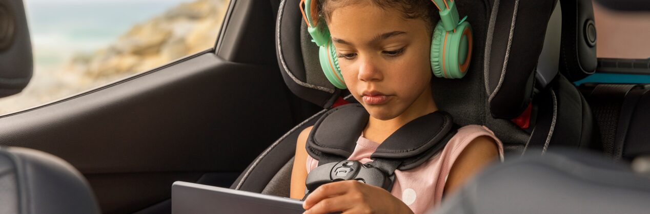 Little Girl in Car Seat Using iPad with Headphones