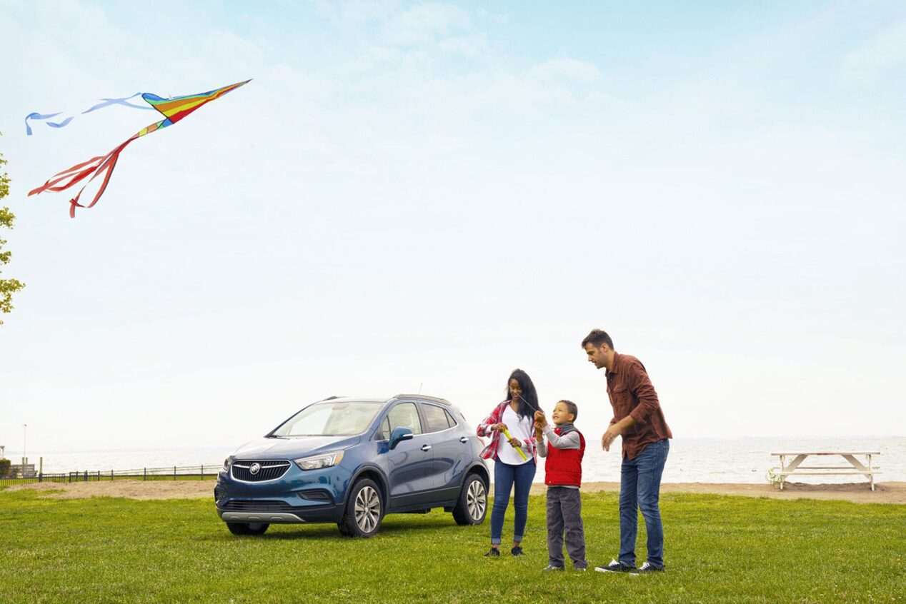 Family Enjoys Kites In a Field In front of Their Buick