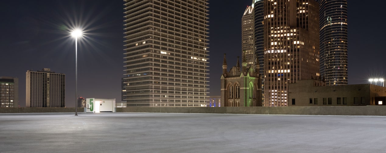 Empty Parking Lot in a City With Overhead Lights On