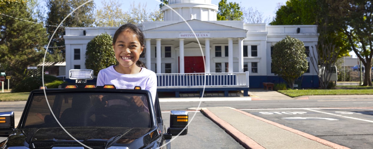 Little Girl Riding in Mini GMC Play Car Down a Road