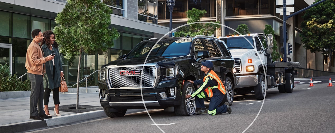 Roadside Assistance Works on a GMC SUV in Front of an Office Building