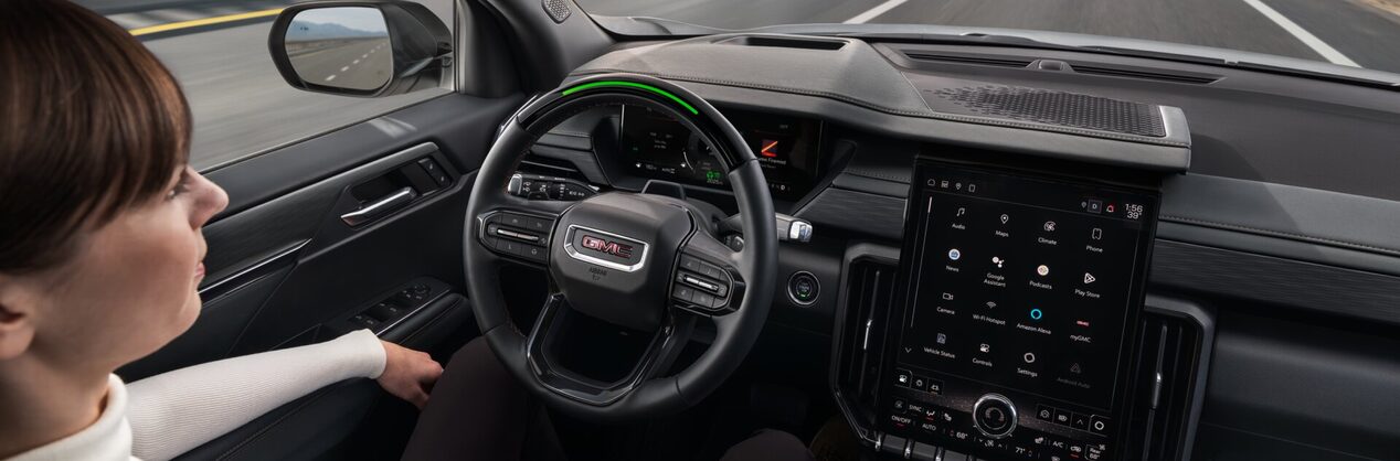 A couple driving down the road using Super Cruise hands-free driving assistance technology