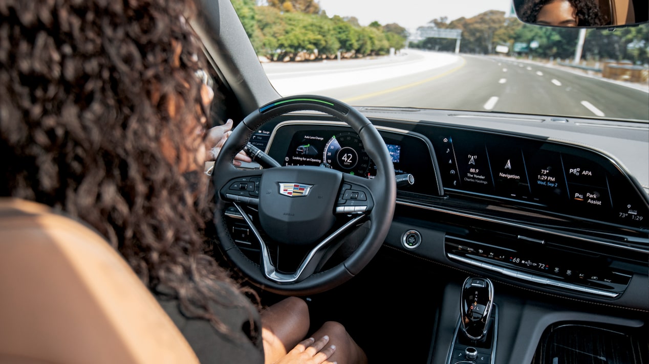 Over-the-shoulder view of a woman using Super Cruise hands-free driving technology while driving on the freeway