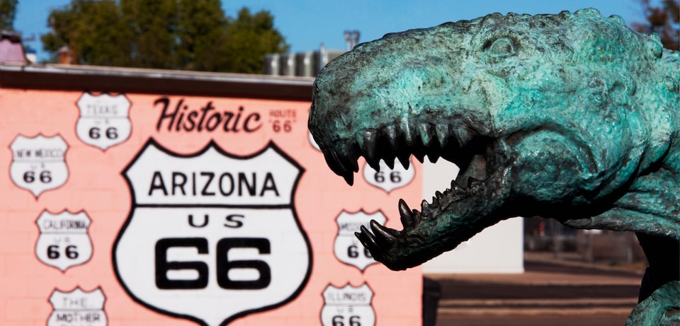 A historic Arizona Route 66 sign next to a dinosaur statue