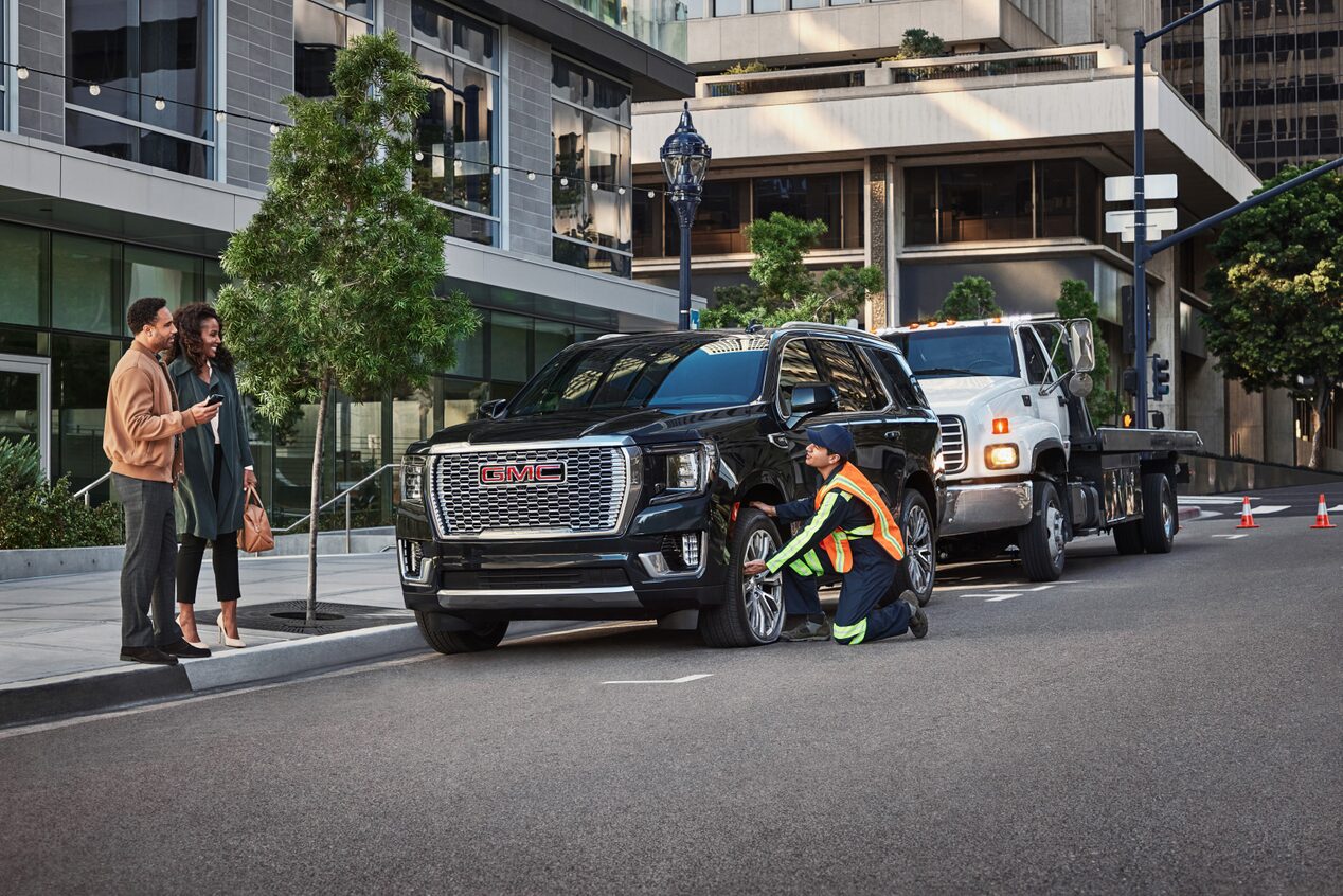 Roadside Assistance Works on a GMC SUV in Front of an Office Building