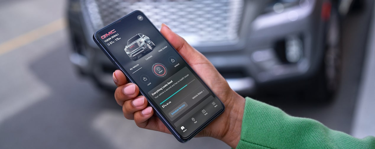 Hand Holds myGMC Mobile App in Front of Vehicle